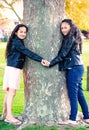 Two Maori sisters holding hands hugging a tree