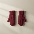 Two maroon knitted mittens with a cable knit pattern are displayed side by side on a Royalty Free Stock Photo