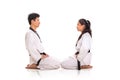 Two martial art practitioners sitting face to face on their knees, full length