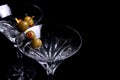 Two martini glasses with olives on black