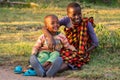 Two Masai children sitting on grass together