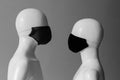 Two masked mannequin faces look at each other. Man and woman during the epidemic