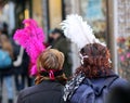 Two masked women with big feathers around Venice Italy