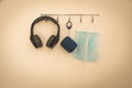 Two masks hung on a coat hanger together with headphones and wireless speaker on a white textured background