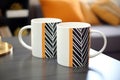 two matching designer coffee mugs on a table Royalty Free Stock Photo