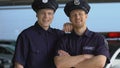 Two mates in police uniform and cap smiling, looking into camera, trainees