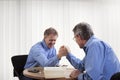 Two mature businessman or lawyer doing arm-wrestling in an office