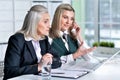 Two mature businesswomen sitting at table with laptop and working together Royalty Free Stock Photo