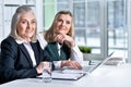 Two mature businesswomen sitting at table with laptop and working together Royalty Free Stock Photo