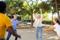 Two mature couples playing volleyball in summer park