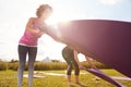 Two Mature Female Friends Laying Out Exercise Mats On Grass At Outdoor Yoga Retreat Royalty Free Stock Photo