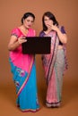 Two mature Indian women using laptop computer and looking shocked and surprised Royalty Free Stock Photo