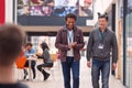 Two Mature Male Students Or Teachers Walking Through Communal Hall Of Busy College Campus Building Royalty Free Stock Photo