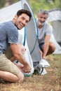 Two mature men erecting tent