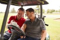 Two Mature Men Playing Golf Marking Scorecard In Buggy Driving Along Course Royalty Free Stock Photo