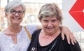 Two mature sisters or friends embraced outdoor looking at camera smiling Royalty Free Stock Photo