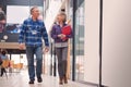 Two Mature Students Or Teachers Walking Through Communal Hall Of Busy College Campus Building Royalty Free Stock Photo