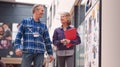 Two Mature Students Or Teachers Walking Through Communal Hall Of Busy College Campus Building Royalty Free Stock Photo