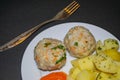 Two meat meatballs with boiled potatoes and boiled carrots on a white plate with a fork on a dark background. Close up Royalty Free Stock Photo