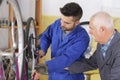 Two mechanics fixing bicycles wheel in workshop