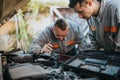 Two mechanics inspect a car engine under the hood using a flashlight for precise repair work Royalty Free Stock Photo