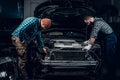 Two mechanics repairng a car.