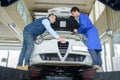 Two mechanics working on car engine at garage Royalty Free Stock Photo