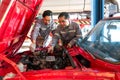 Two mechanics are working on a car with the hood open in an automotive shop or garage. They seem focused and engaged in diagnosing Royalty Free Stock Photo