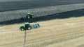 Two mechanized ploughs are simultaneously riding along the field