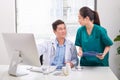 Two medical doctors consulting, smiling at office desk