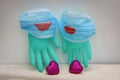 Two medical masks with painted red lips are worn on surgical gloves. Next to two scarlet hearts