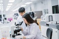 Two  scientist working in Medical laboratory , young female scientist looking at microscope. select focus in young female Royalty Free Stock Photo