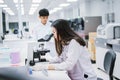 Two  scientist working in Medical laboratory , young female scientist looking at microscope. select focus in young female Royalty Free Stock Photo