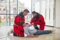 Two medical workers in red uniform halping a faint woman