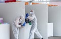 Two medical workers in white protective suit disinfect and clean public place with spray sanitizer to stop spreading virus Royalty Free Stock Photo