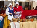 Two medieval peasant women in national Spanish costumes are trading in the market square Royalty Free Stock Photo