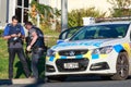 Two armed members of the New Zealand police in front of a police car