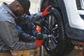 Two men auto mechanics changing car tire on a vehicle on a hoist using an electric drill to loosen the bolts Royalty Free Stock Photo