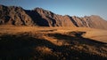 Two men with backpacks are trekking along a mountain plateau high in the mountains surrounded by rocky mountains in late