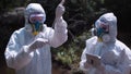 Two men in biohazard suits sampling water