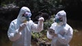 Two men in biohazard suits sampling water