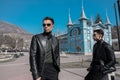 Two men in black clothing style are standing in the city of Pyatigorsk, Stavropol Territory, in a park, a flower garden posing for