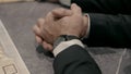 Two men in black suits put their hands on the table in a meeting.