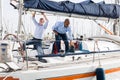 Two men in blue shirts and jeans working on sailing yacht in the port