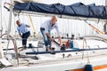 Two men in blue shirts and jeans working on sailing yacht in the port