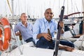 Two men in blue shirts relaxing on sailing yacht in the port