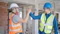 Two men builders shake hands speaking at construction site
