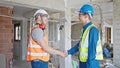 Two men builders shake hands speaking at construction site