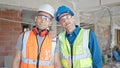 Two men builders standing together with relaxed expression at construction site