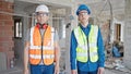 Two men builders standing together with relaxed expression at construction site